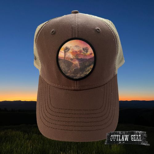 A brown trucker hat featuring a sunset silhouette over Bear Valley with the text "WhyILoveMontana."