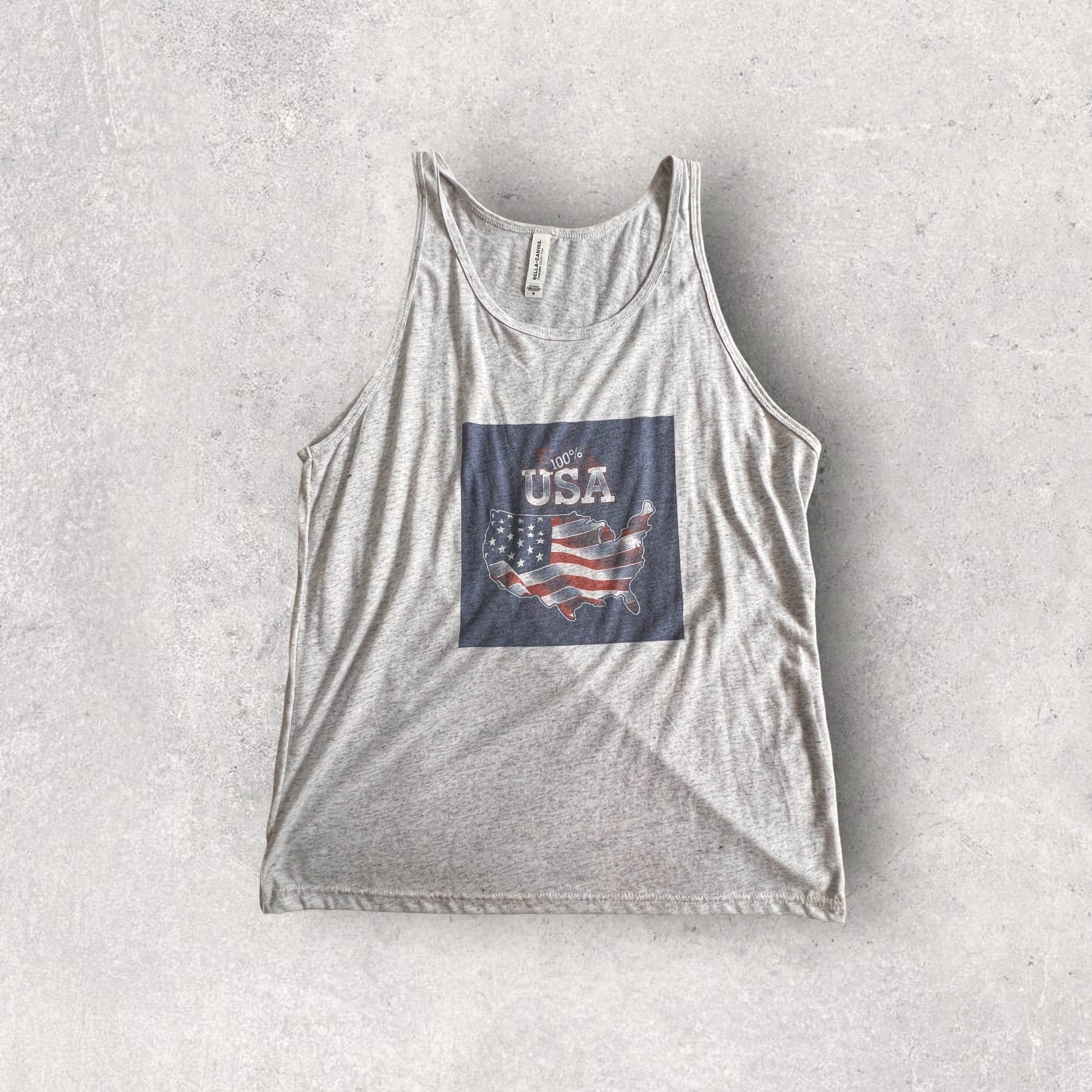 A triblend tank with a "100% USA" design, perfect for showing pride in American-made products, featuring an American flag emoji.