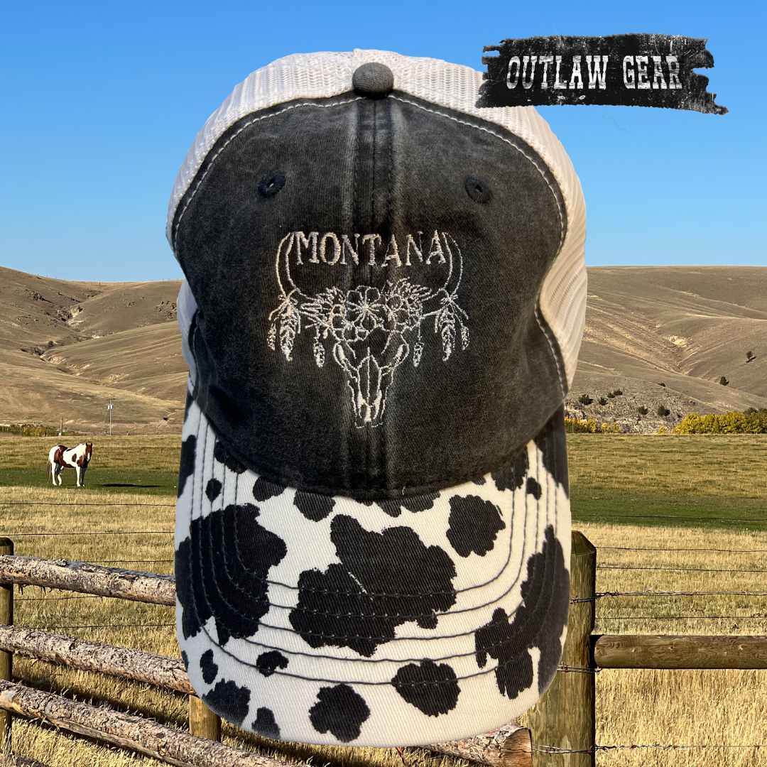 Image of the Montana Cow with Feathers Cow Print Hat featuring a unique cow print design adorned with feathers, perfect for adding Western flair to any outfit.