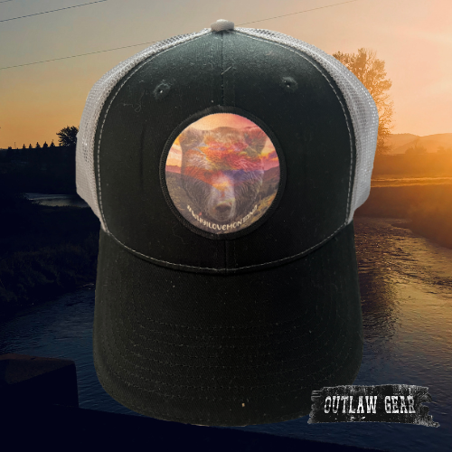 A black trucker hat with a sunset silhouette over Bear Valley and the text "WhyILoveMontana."